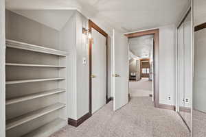 Hallway featuring light carpet and baseboards