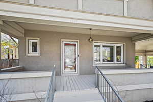 Doorway to property featuring a deck and stucco siding