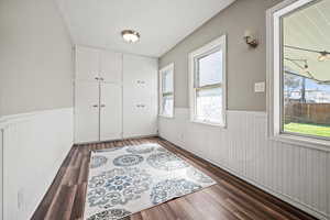 Unfurnished room featuring wainscoting and dark wood-type flooring