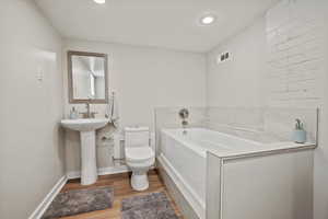 Bathroom featuring a garden tub, wood finished floors, and recessed lighting