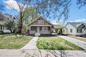 View of front of home with a porch, a front yard, a carport, concrete driveway, and stucco siding