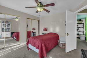 Bedroom with carpet floors, two closets, and ceiling fan