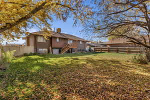 Rear view of property featuring a fenced backyard, a chimney, brick siding, and stairway