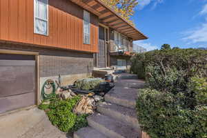 View of property exterior with brick siding, a balcony, and a garage