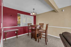 Dining space featuring beamed ceiling, carpet flooring, and a chandelier