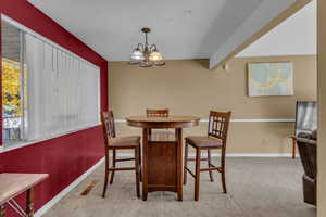 Dining space featuring light carpet and a chandelier