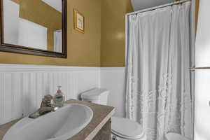 Bathroom with wainscoting, vanity, and a shower with curtain