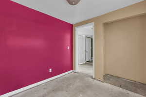 Unfurnished room with concrete floors and baseboards