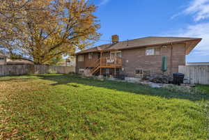 Rear view of house with a fenced backyard, stairway, a patio, brick siding, and a wooden deck