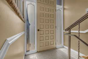 Foyer with light tile patterned floors and stairs