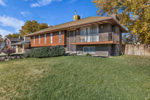 Back of property featuring brick siding, a chimney, a yard, and a shingled roof