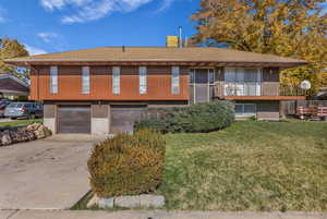 View of front of house featuring brick siding, concrete driveway, a garage, roof with shingles, and a front lawn