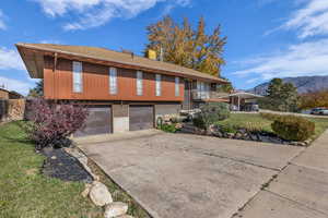 View of front facade with brick siding, concrete driveway, a mountain view, an attached garage, and a balcony