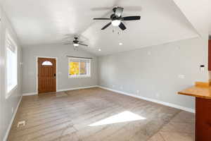 Foyer with light colored carpet, lofted ceiling, ceiling fan, and light tile patterned floors