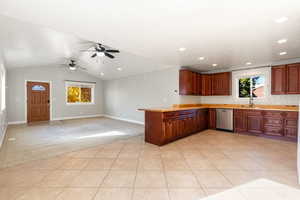 Kitchen with light carpet, light tile patterned floors, backsplash, lofted ceiling, and stainless steel dishwasher