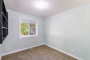 Carpeted empty room with baseboards and a textured ceiling