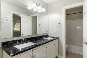 Full bathroom featuring double vanity, light tile patterned floors, and  shower combination