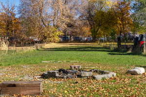 View of yard featuring an outdoor fire pit and view of scattered trees