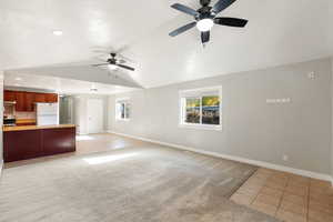 Unfurnished living room featuring light tile patterned flooring, light carpet, vaulted ceiling, ceiling fan, and recessed lighting