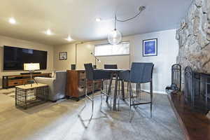 Carpeted dining area with a stone fireplace and baseboards