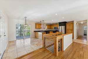 Kitchen with recessed lighting, dark countertops, brown cabinets, decorative light fixtures, and appliances with stainless steel finishes