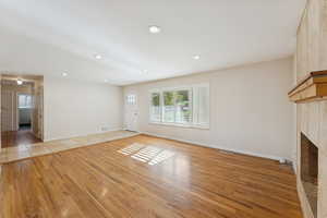 Unfurnished living room with light wood-style floors, recessed lighting, and a fireplace