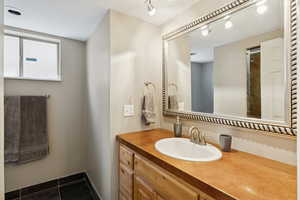 Bathroom featuring vanity, dark tile patterned floors, a closet, and a shower with door