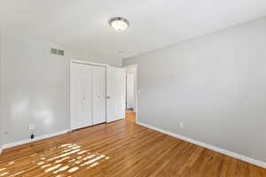 Unfurnished bedroom with light wood-style floors and a closet