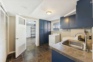 Laundry room with stone tile floors, cabinet space, and washing machine and clothes dryer