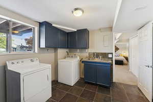 Washroom featuring dark carpet, independent washer and dryer, cabinet space, and dark stone finish flooring