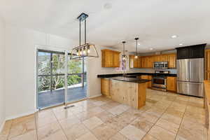 Kitchen with a chandelier, stainless steel appliances, decorative light fixtures, recessed lighting, and brown cabinetry