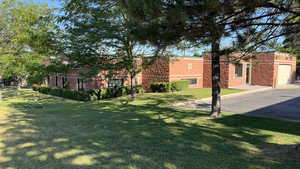 View of green lawn featuring driveway and a garage