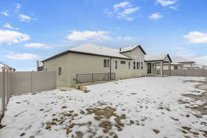 Snow covered rear of property with a patio and stucco siding