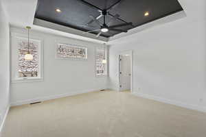 Unfurnished room featuring a raised ceiling, light carpet, a ceiling fan, and recessed lighting