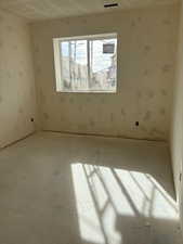 Carpeted empty room with wallpapered walls and a textured ceiling