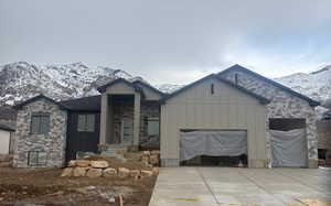 View of front of home featuring stone siding, board and batten siding, a mountain view, and a garage