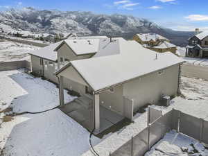 View of snowy exterior with a fenced backyard, a mountain view, a residential view, and a patio