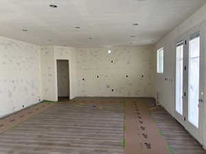 Spare room with wallpapered walls, wood finished floors, and a textured ceiling