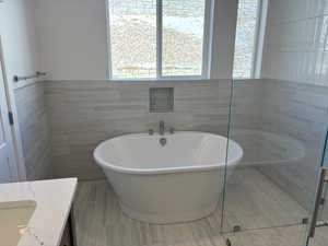 Bathroom featuring vanity, tile walls, and a freestanding tub