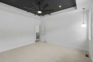 Empty room with light carpet, a raised ceiling, ceiling fan, and recessed lighting