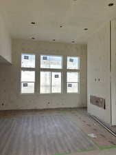 Unfurnished living room featuring wallpapered walls and wood finished floors