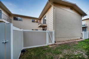 View of property exterior featuring a gate, a balcony, and brick siding