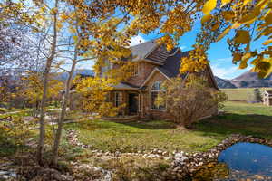 Traditional home featuring stone siding, a front lawn, roof with shingles, and a mountain view