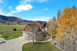 Side view of front of house with a front yard, a mountain view, stone siding, and driveway