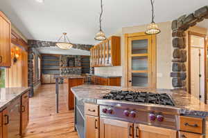 Kitchen featuring hanging light fixtures, stainless steel gas range, a kitchen bar, and pantry