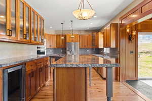 Kitchen with 2 islands, wraparound custom cabinets,  beverage cooler, hanging light fixtures, and access to the dining room