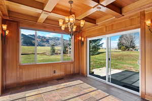Dining room featuring custom wood coffered ceiling, a mountain view, 2 exterior sliding glass doors, and a chandelier