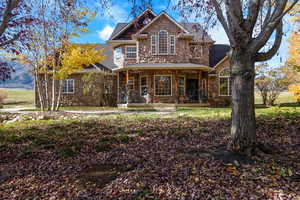 Traditional home featuring stone and cedar shake, a porch, and a shingled roof