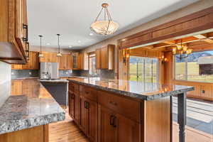 Kitchen looking into dining room with mountain views, custome cabinetry, decorative light fixtures, stone countertops, and breakfast island