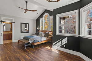 Primary bedroom featuring vaulted ceiling, dark wood-type flooring, ceiling fan, and ensuite bath